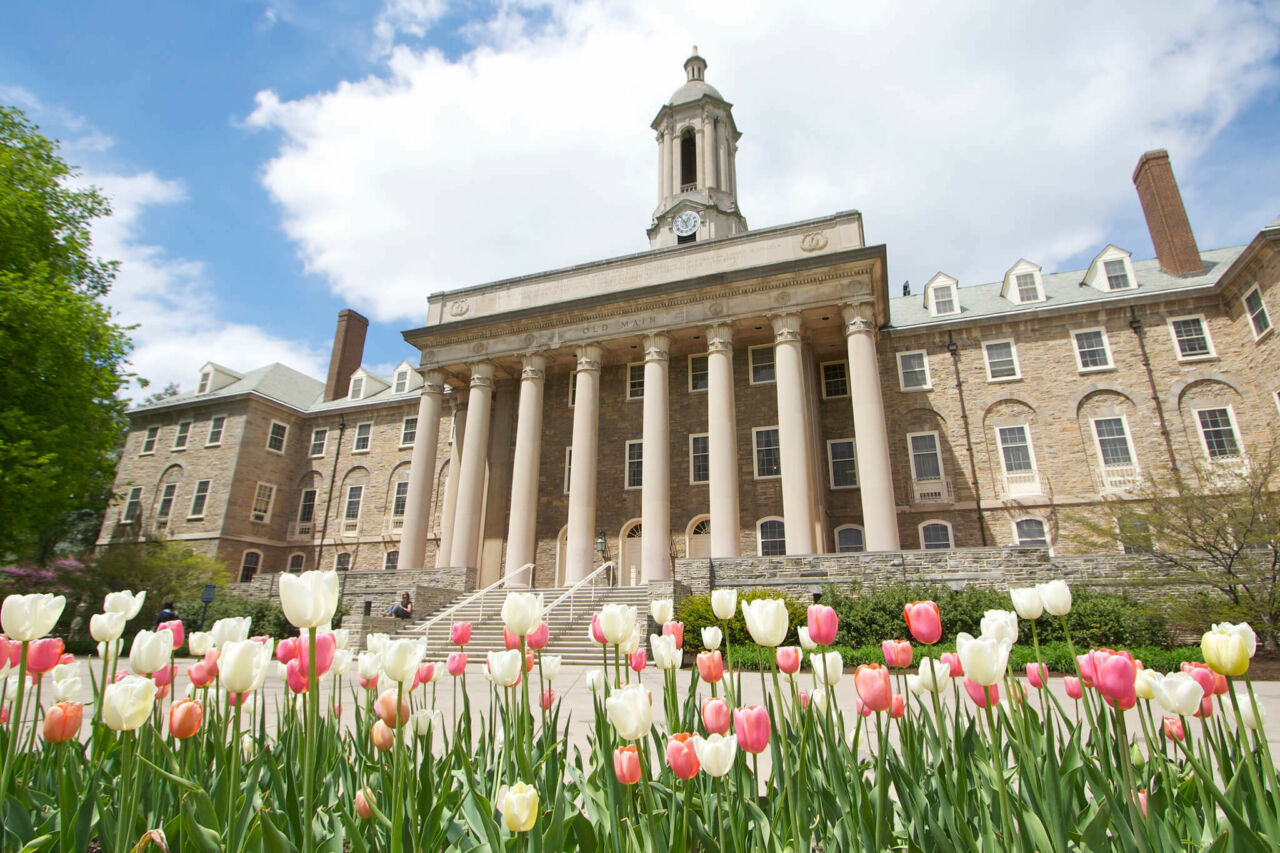 Old Main building from low angle on spring day with pink and yellow tulips in foreground.