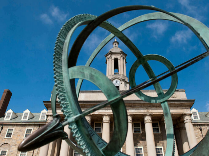 Old main blue sky with metal sculpture in foreground.