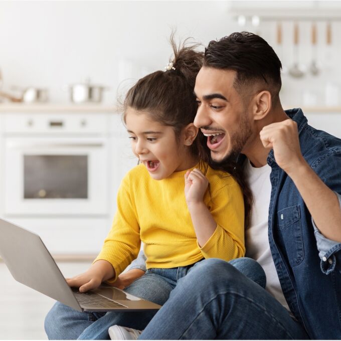 Father and daughter playing a computer game on a laptop.