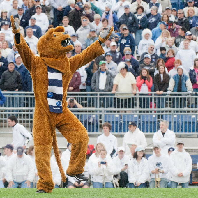 Nittany Lion mascot raises arms to encourage crowd to cheer at blue and white football game in Beaver Stadium.