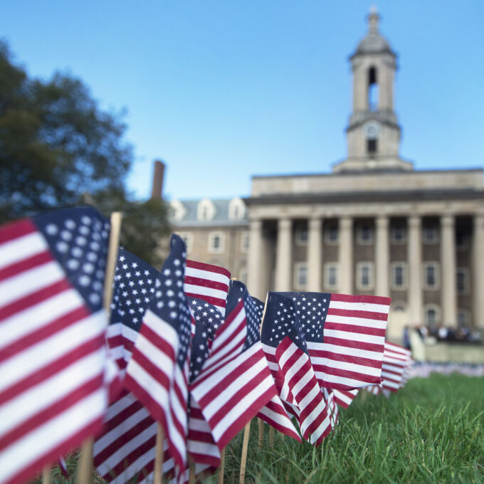 American flags in grass in front of Old Main on Penn State University Park campus.